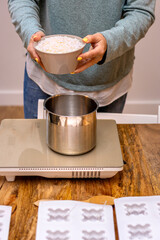Soy wax candles. Young woman with yellow painted nails and a bowl full of soy wax to boil.