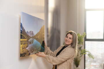 Girl hanging a photo canvas on a wall