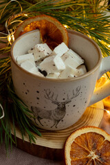 Marshmallows in a cup, dried orange and Christmas tree branches near the cup