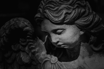 Close up black and white image of ancient statue of guardian angel.