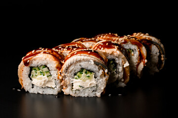 Sushi rolls Philadelphia with smoked eel, avocado, cream cheese on dark background.