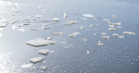 Close up of ice cracks on frozen lake in winter. Layer of freezing water on top of river. Ice-covered pond