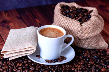 coffee beans on wooden table with cup of coffee and napkin