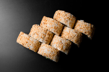 top view on sushi rolls california with decorated with sesame seeds on dark background.