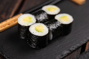 Maki sushi roll with avocado with chopsticks. Sushi menu. Japanese food.