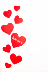 Imagen vertical de corazones rojos recortados sobre un fondo blanco con el mes de Febrero escrito en uno 