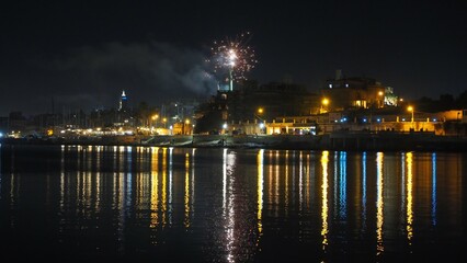Fototapeta na wymiar Fireworks display with light reflection on water on NYE - Manoel Island Malta