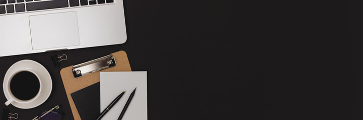 Banner with stationery, laptop and cup of coffee on a black background. Workspace for e-learning with copy space.
