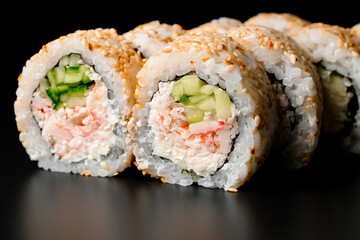 Close-up of tasty sushi rolls california with snow crab meat garnished sesame seeds on dark background.