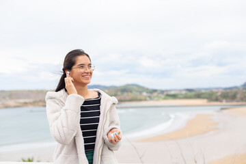 Hispanic lady with smartphone listening to music in wireless earphones