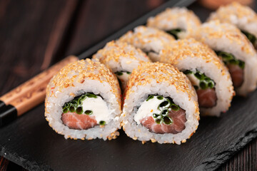 Sushi roll with salmon, green onion and cottage cheese with sesame close-up - Sushi menu. Japanese food.
