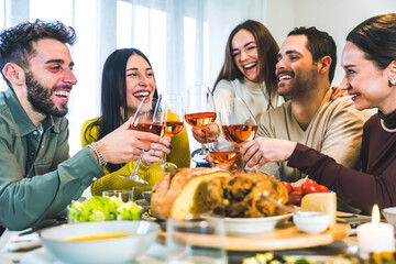 Group of happy friends toasting rose wine glasses , Young smiling friends having fun at dinner party home-Cheerful guys enjoying time together at table eating meals-Dining Concept-Focus on glasses 