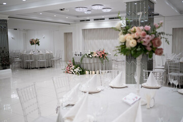 Centerpiece made of green leaves and fresh flowers stands on the dinner table. Wedding day. Fresh flowers decorations. Peony arrangements.