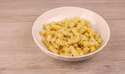 Spiral pasta in a white plate on a wooden table