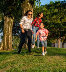 lesbian female couple. playing, running and having fun with their adopted son in the park, real people, green background, copy space.