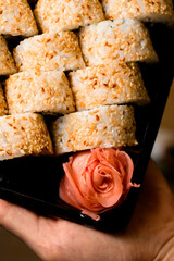 top view of rose shaped pickled ginger and california sushi rolls garnished sesame seeds