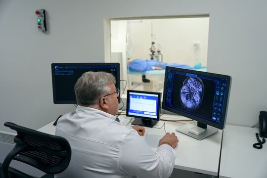 Elderly doctor looks into the monitor of diagnostic equipment