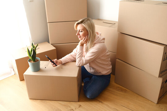 Young woman moving to a new house and using mobile phone. Home sweet home
- Powered by Adobe