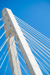 a abstract image of a bridge pillar with support cables against blue skies  