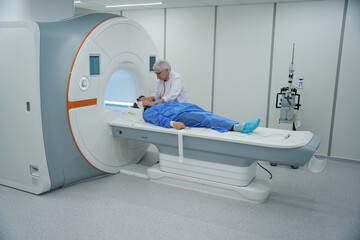 Woman diagnostician prepares a patient for an MRI procedure