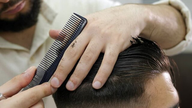 A man cuts hair at a hairdresser-stylist in a barbershop. Scissors comb close-up. Hairdressing services.