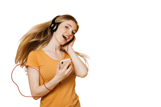 Adorable redhead young woman enjoying great sound in new headphones, sings loudly, holds cellular, smiles broadly, wears orange casual clothes, over transparent background. Sincere people emotions. - Powered by Adobe