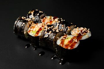 vegetarian sushi rolls with tofu and rice wrapped in nori drizzled with soy sauce and sesame seeds.