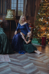 Mom and daughter on New Year's Eve are sitting in a Scandinavian-style room in light warm sweaters with long flowing hair , happy and hugging