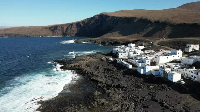 One of Lanzarote's less-known coastal towns, Tenesar is truly a beautiful little spot to appreciate Lanzarote's western coast - Drone arial view of white village houses and sae storm with waves surf 