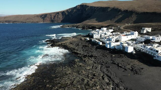 One of Lanzarote's less-known coastal towns, Tenesar is truly a beautiful little spot to appreciate Lanzarote's western coast - Drone arial view of white village houses and sae storm with waves surf 