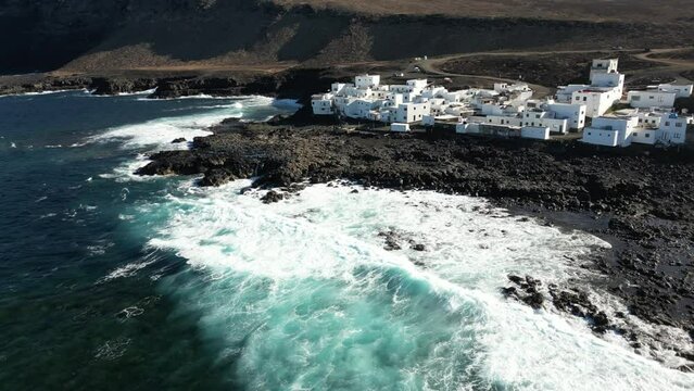 One of Lanzarote's less-known coastal towns, Tenesar is truly a beautiful little spot to appreciate Lanzarote's western coast - Drone arial view of white village houses and sae storm with waves surf 