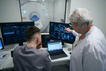 Woman doctor and her colleague are analyzing results of CT - obrazy, fototapety, plakaty