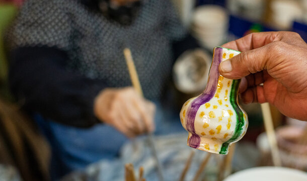 elderly craftswoman painting earthenware in her pottery workshop