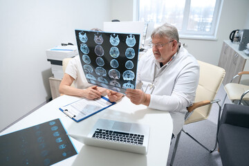 Doctor and the patient are studying MRI images in office
