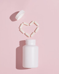 White pills for treatment in heart shape on pink background. Mockup for advertising or other ideas....
