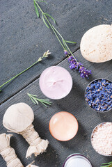 beauty product samples with fresh purple and blue dried lavenders, bath salts and massage pouches on dark wood table background