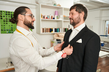 Experienced couturier trying on new custom-made clothes on gentleman