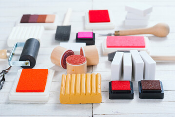 handicraft equipments, ink pads, lino cutter, paint roller and plasticine blocks on white wood table