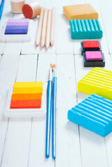 plasticine blocks, ink pads and pencils, brushes on white wood table