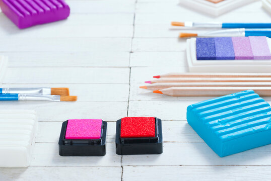 plasticine blocks, ink pads and pencils, brushes on white wood table
