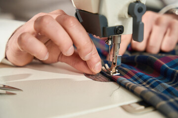 Experienced tailor is threading sewing machine before work