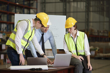 Caucasian engineers, architect, industrial worker have meeting, with laptop and blueprint on the table inside the factory, concept teamwork, construction worker, industrial occupation. 