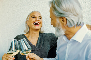 mature senior couple laughing and drinking wine.