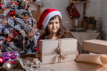 a happy little girl at home in the kitchen is packing Christmas presents in crab boxes. new year's sale