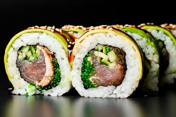 Close-up of green dragon sushi rolls with salmon, avocado, cucumber and green caviar. Dark background