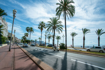 Fototapeta na wymiar Embankment of French Riviera and warm Mediterranean Sea . Beach along Promenade des Anglais in Nice town with fantastic landscape with tall palm trees