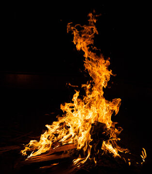 Ein hohes Lagerfeuer in der Nacht vor schwarzem Hintergrund