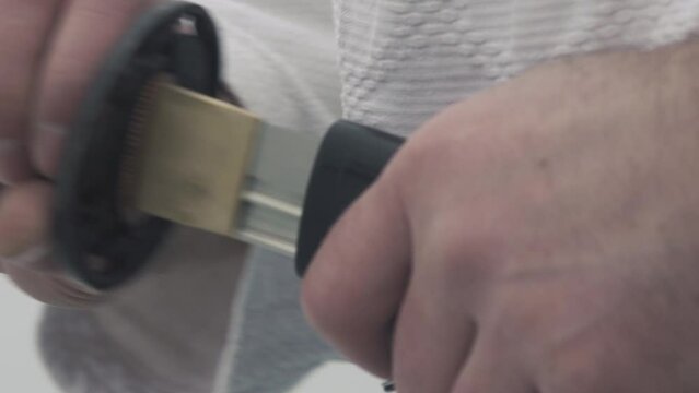 man takes katana covered with samegawa made of stingray skin out of special case and practices moves closeup slow motion