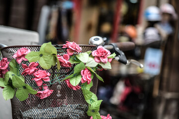 Ein Fahrrad steht auf der Straße. Im Fahrradkorb sind Blumen.