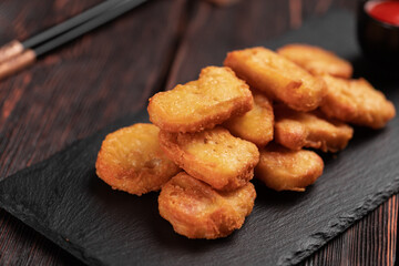 Fried chicken pieces on stone board with chopsticks - asian food close-up